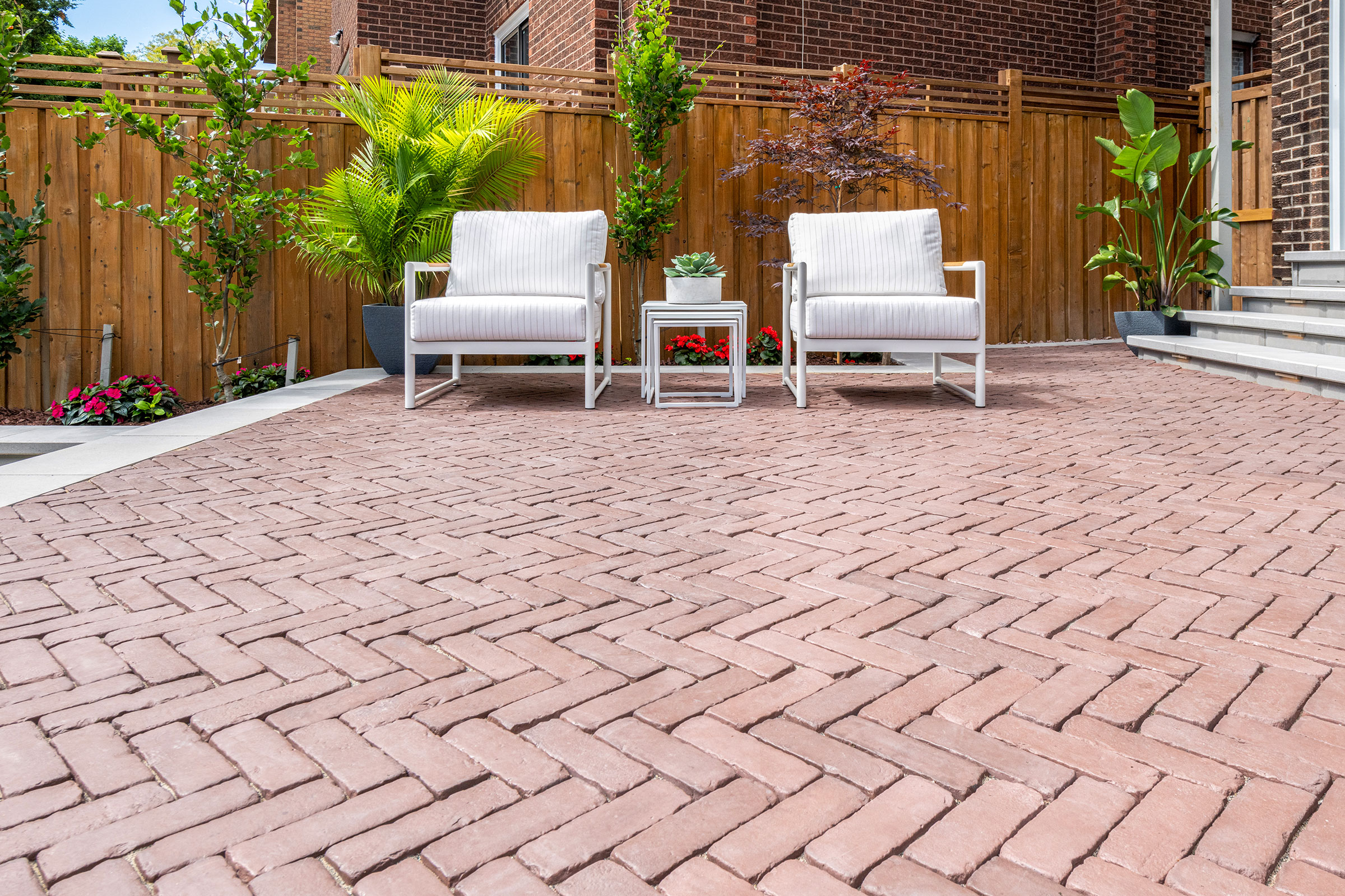 Herringbone brick paver patio with white lounge chairs